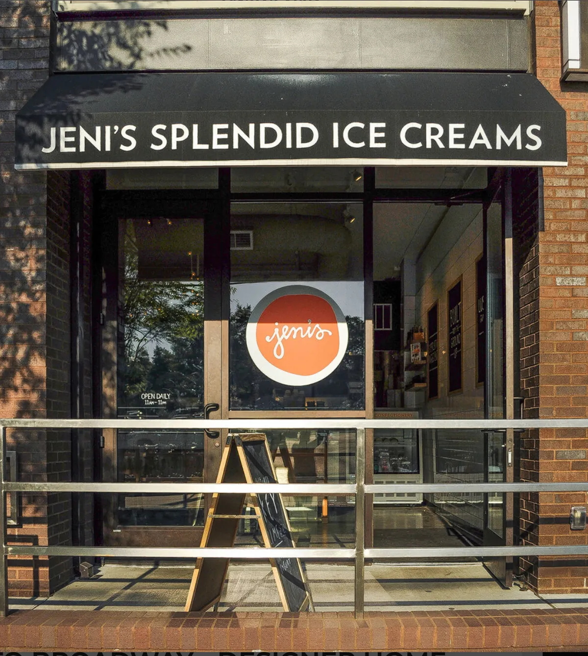 The image shows the cheerful storefront of an ice cream shop, featuring welcoming signage, an outdoor seating area, and a visible menu board. The scene is lively and inviting, suggesting a place where people gather for treats and social moments.